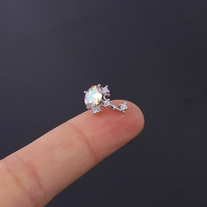 Macro shot of silver key-shaped ear stud with iridescent opal and sparkling cubic zirconia
