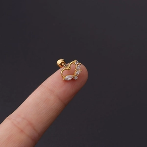 Close-up of golden heart-shaped helix earring with white zircon inlay and screw ball back