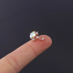 Macro shot of rose gold key piercing stud with iridescent opal and white zircons