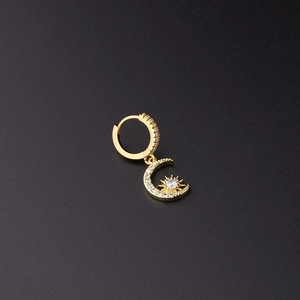 Detalle de pendiente de luna chapado en oro con circonitas y motivo de sol central