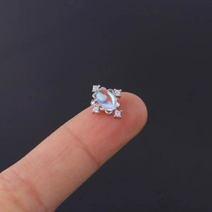 Macro detail of silver moonstone piercing stud with cz accents held on a finger