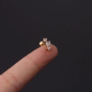 Macro shot of gold stainless steel cartilage stud with three curved zircons and ball back