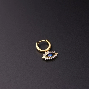 Detalle de pendiente ojo turco dorado con circón azul y cristales sobre fondo negro