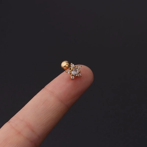 Detailed view of gold stainless steel stud earring with cubic zirconia held by fingertips