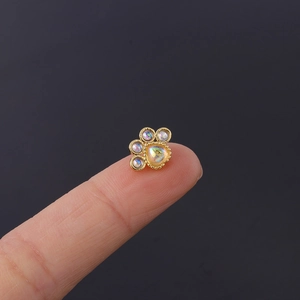 Macro shot of gold cat paw piercing with iridescent stones shown on a fingertip