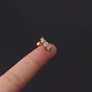 Macro view of a 16G gold cartilage stud earring with three vertical cubic zirconia stones