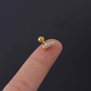 Macro detail of a 16G gold piercing stud with five clear zircons and screw ball back