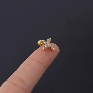 Macro detail of a 16G gold cross stud earring with white zircons and a screw ball back