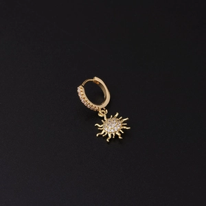 Detalle del pendiente de oro con circonitas y colgante de sol brillante en negro