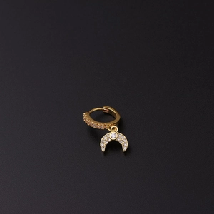 Vista detallada de un pendiente huggie dorado con colgante de luna creciente y circonitas