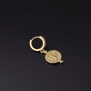 Macro detail of a gold-plated hoop earring with a sparkling bee pendant and micro-pave stones