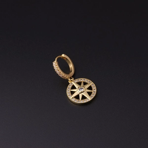 Detail of gold starburst hoop earring with micro-pave white zircons on black background