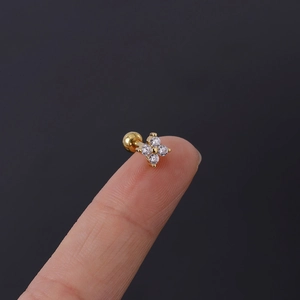 Macro detail of tiny 16G clover cartilage stud earring with cubic zirconia held by hand