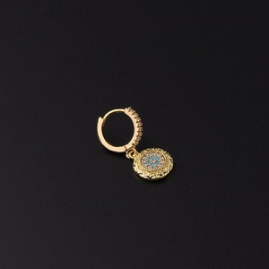 Detalle de aro dorado con textura martillada, piedra azul y circonitas incrustadas