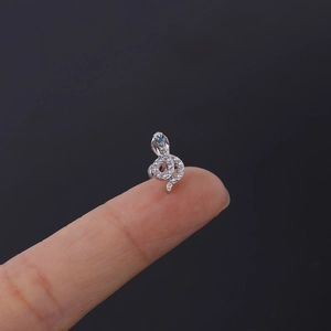 Macro shot of silver snake cartilage earring with white zircons on a fingertip