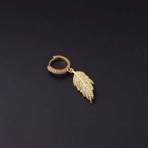 Detail of a gold leaf earring with micro-pave crystals on a black textured background