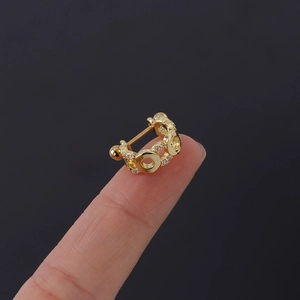 Vue macro détaillée d'un clou d'oreille en cuivre doré avec zircone sur le bout du doigt