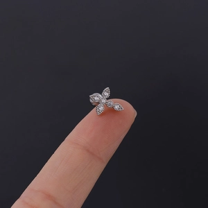 Macro detail of tiny silver butterfly stud earring with clear cubic zirconia on fingertip