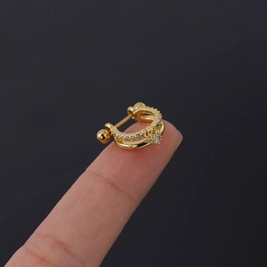 Vue macro d'un petit clip d'oreille doré avec gravure LOVE et zircons sur un doigt