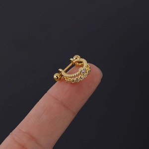 Gros plan d'un clou d'oreille cartilage doré à double rangée de zircons sur les doigts