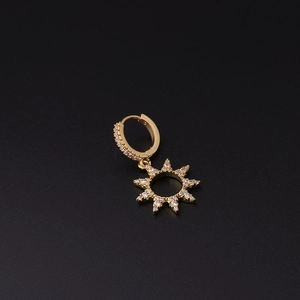 Exquisite golden sunburst earring with micro-paved zircons on a dark textured background