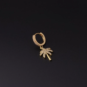 Detail view of a gold palm tree earring charm with cubic zirconia on black background