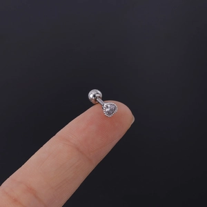 Macro shot of 16G stainless steel heart stud with zircon held on fingertip for scale