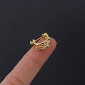 Gros plan d'un piercing en feuille d'or avec zircons clairs posé sur un bout de doigt