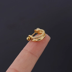 Vue macro d'un piercing d'oreille doré avec deux rangées de zircons cubiques brillants