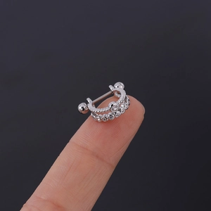 Vue macro d'un piercing d'oreille en argent et zircone tenu sur le bout d'un doigt