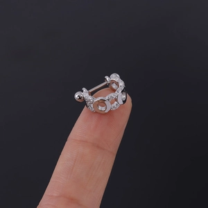 Gros plan d'un piercing cartilage en argent et zircone avec maillons sur le bout du doigt