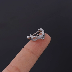 Macro d'un petit piercing d'oreille en forme de V argenté avec zircons sur le bout du doigt