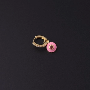 Détail de créole dorée avec zircons blancs et pendentif œil en émail rose et gemme rouge
