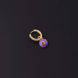 Détail de boucle d'oreille huggie avec pendentif œil en émail violet et pierre zircon rouge