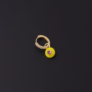 Détail de boucle d'oreille dorée avec zircons et un pendentif œil en émail jaune vif