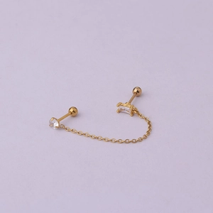 Macro detail of gold double piercing earring with cubic zirconia and connecting chain