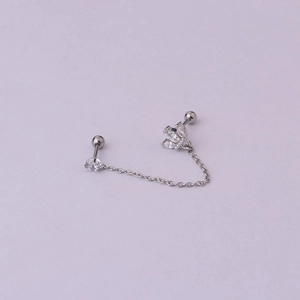 Close-up of silver steel double piercing earring with chain and clear zircon lotus charm