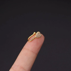 Macro-opname van vergulde hart neusring met zirkonia steentjes op de vingertop