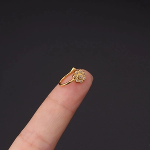 Detail van een gouden nep-neusring met zirkonia bloem getoond op een vingertop voor de maat
