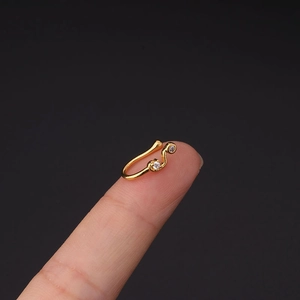 Detailopname van gouden neusring zonder gaatje met zirkonia op een vingertop