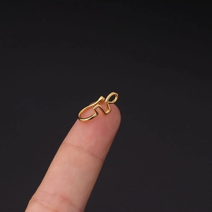 Macro-opname van een gouden nep-neusring op de vingertop om de kleine maat te tonen