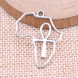 Silver African map Ankh cross pendant on a rustic wooden background with woven fabric