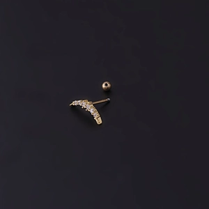 Dettaglio macro del piercing all'orecchio in acciaio dorato con cinque zirconi chiari