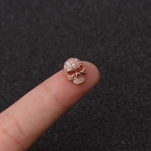 Vista macro de dije de calavera en oro rosa con circonitas sobre las yemas de dedos