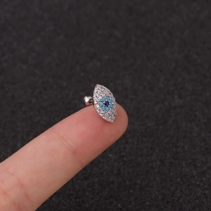 Primer plano de pendiente de ojo en plata con gema azul y circonitas blancas brillantes