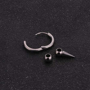 Macro detail of polished stainless steel round hoop earring with punk cone pendant