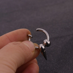 Close-up of a silver punk-style stainless steel ear clip with a sharp cone pendant detail