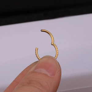Gold stainless steel hinged hoop ring with side-set cubic zirconia stones shown open
