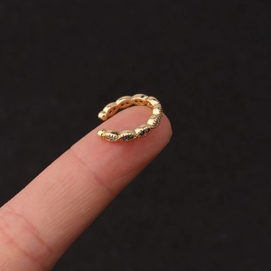 Κοντινό πλάνο χρυσού σκουλαρικιού ear cuff με πολύχρωμα ζιργκόν ανάμεσα στα δάχτυλα