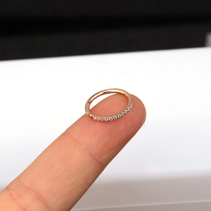 Macro shot of rose gold stainless steel ring with side-set cubic zirconia on a fingertip
